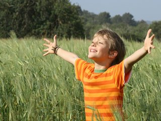 Young child in a field with arms oustretched in joy